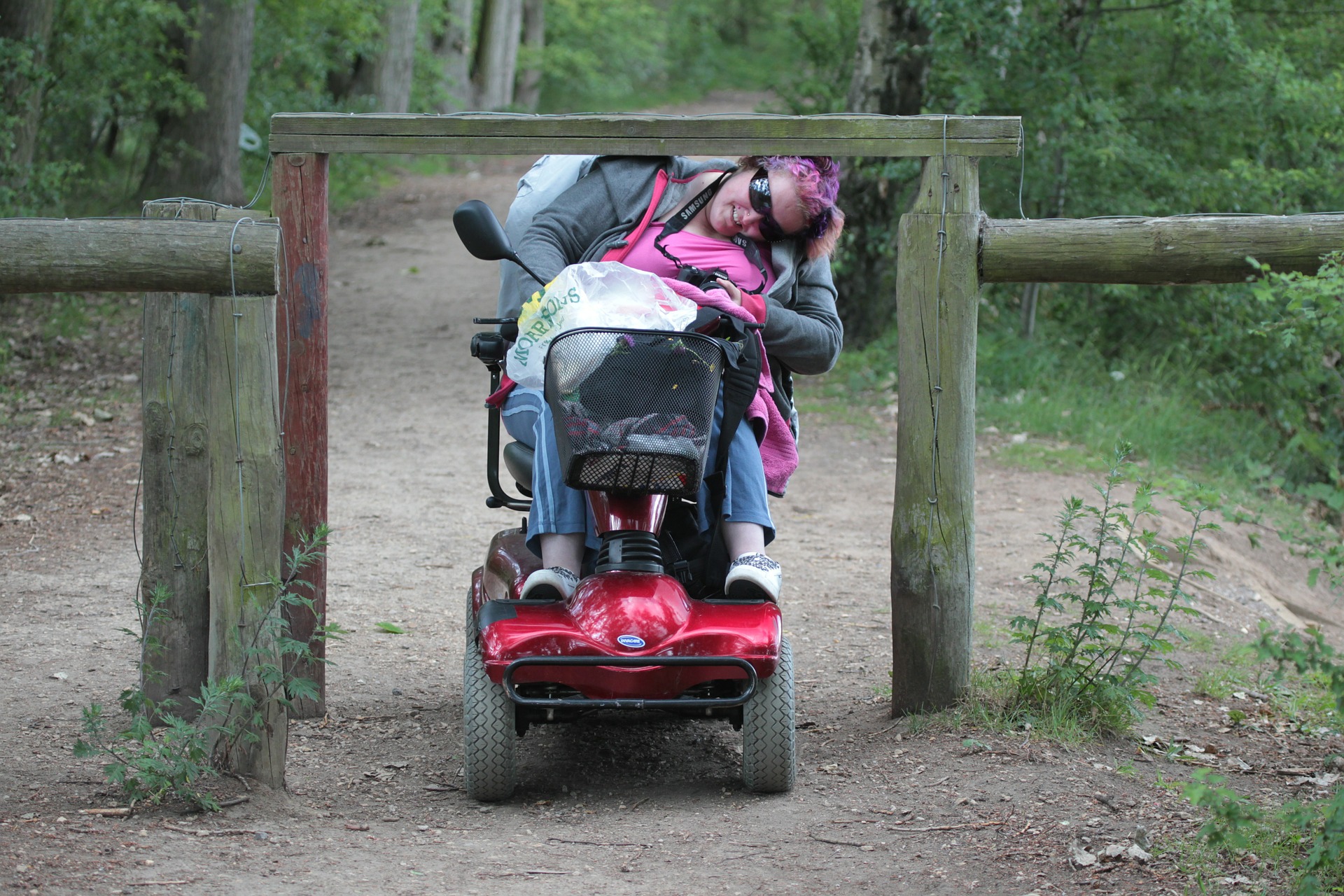 Wheelchair user attempting to enter a dirt trail through an inaccessible gate